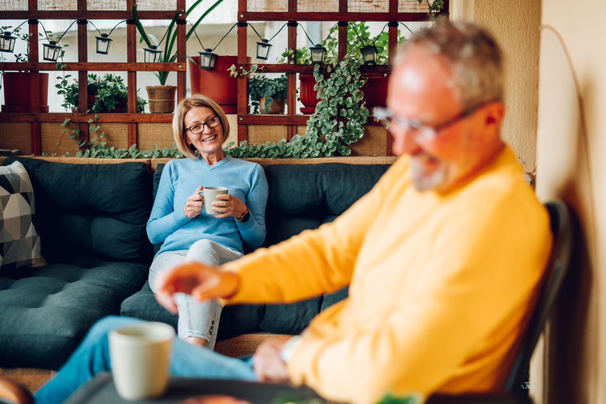 alteres-Paar-trinkt-Kaffee-auf-dem-Balkon-ihres-Hauses